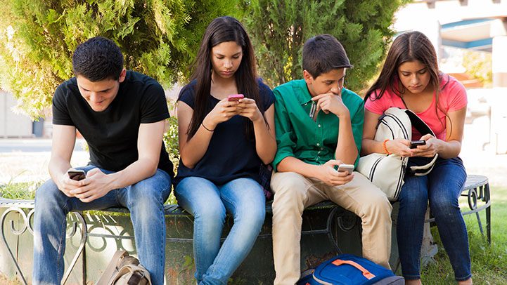 Adolescentes sentados mexendo no celular